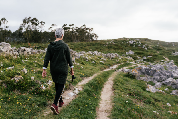 Photo of the back of an older woman walking down a 4 wheel drive track